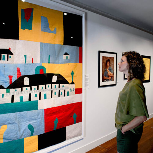A woman contemplates a work of folkart.