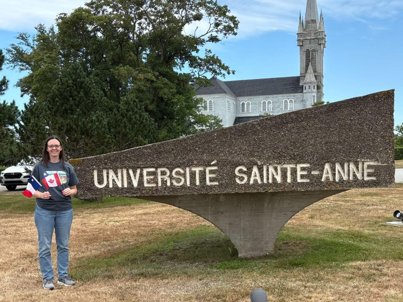 A woman and the Université Sainte-Anne sign